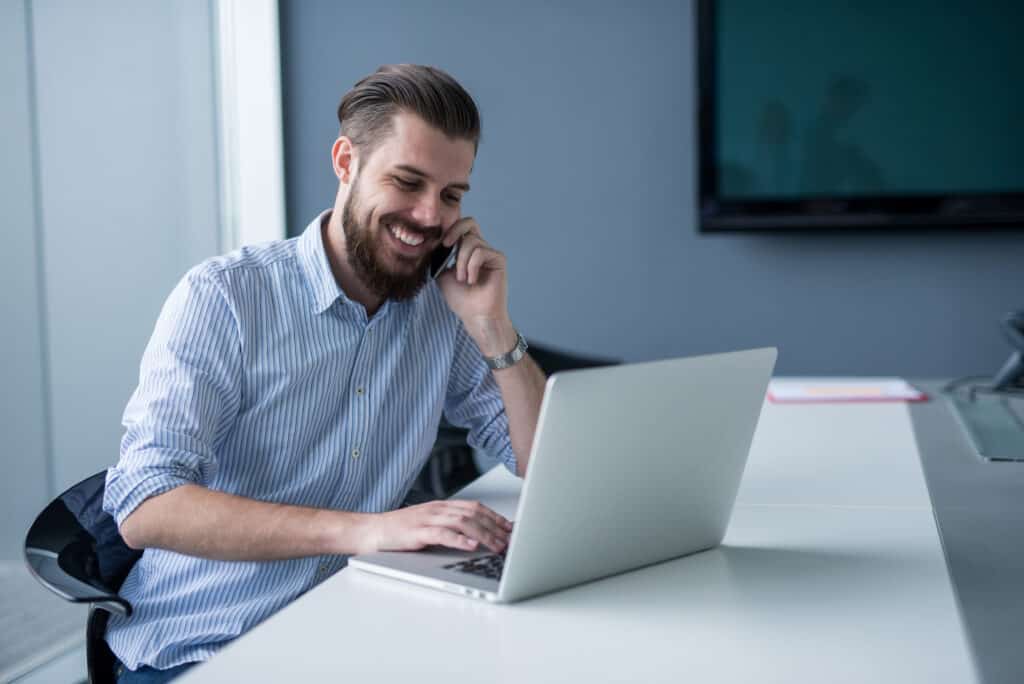 Man in front of laptop looking at it and smiling